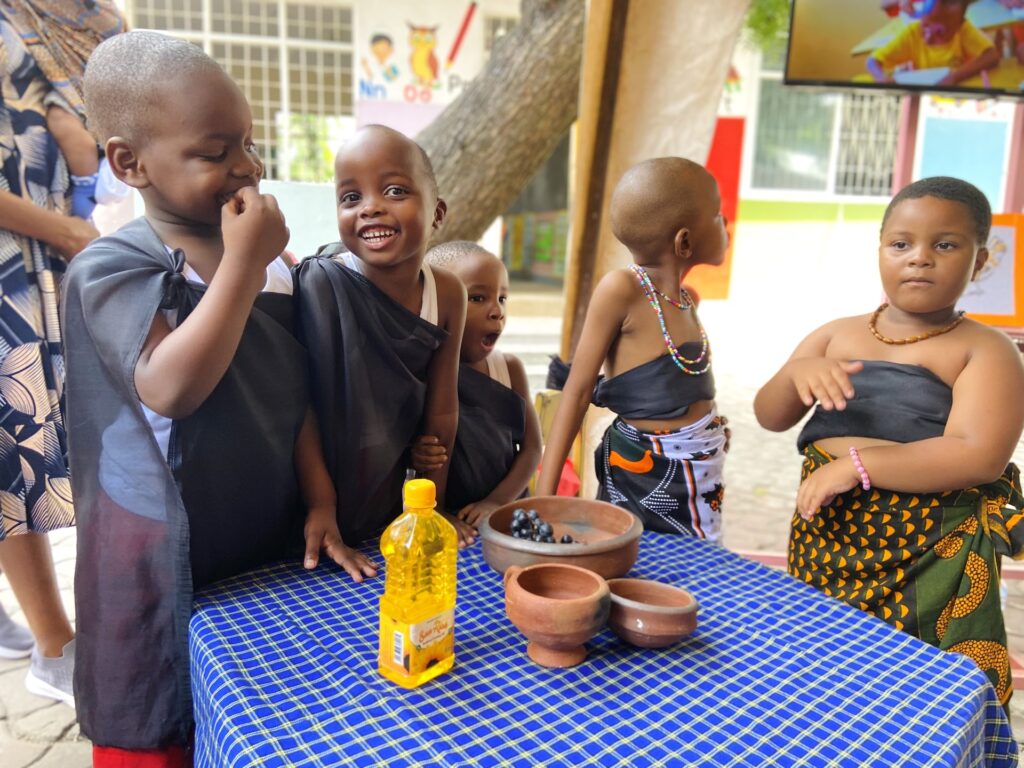 Smiles around the clay-pot display from learners in traditional wraps.