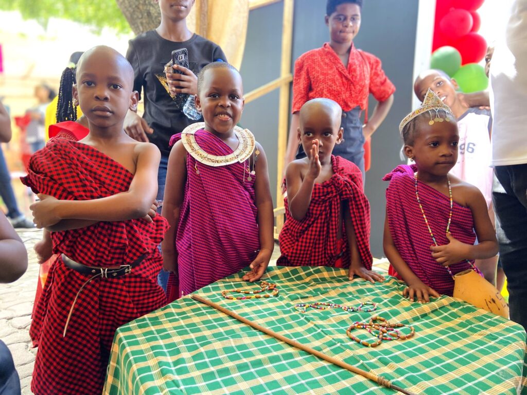 Learners in Maasai shuka present beadwork at their display table.