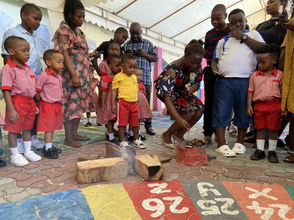 Parents look on as learners demonstrate traditional fire-making.