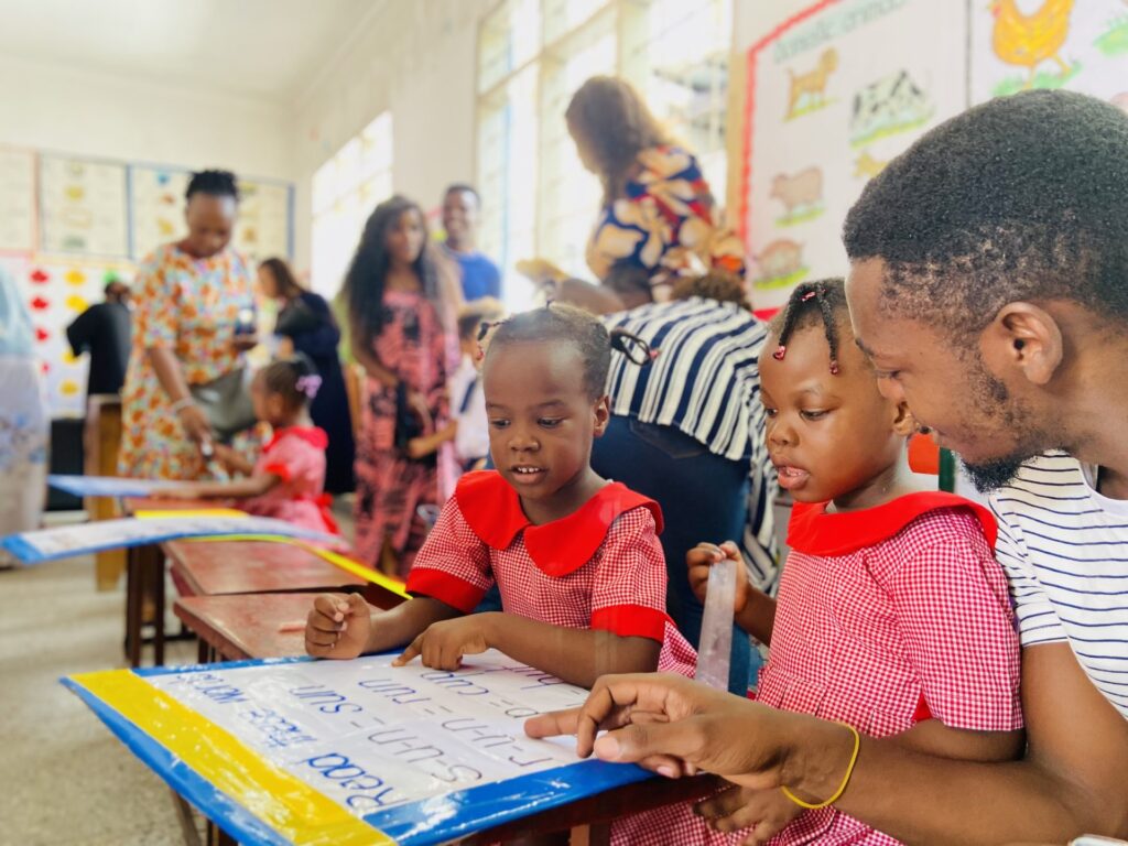 A father follows along as the girls read through their word lists.