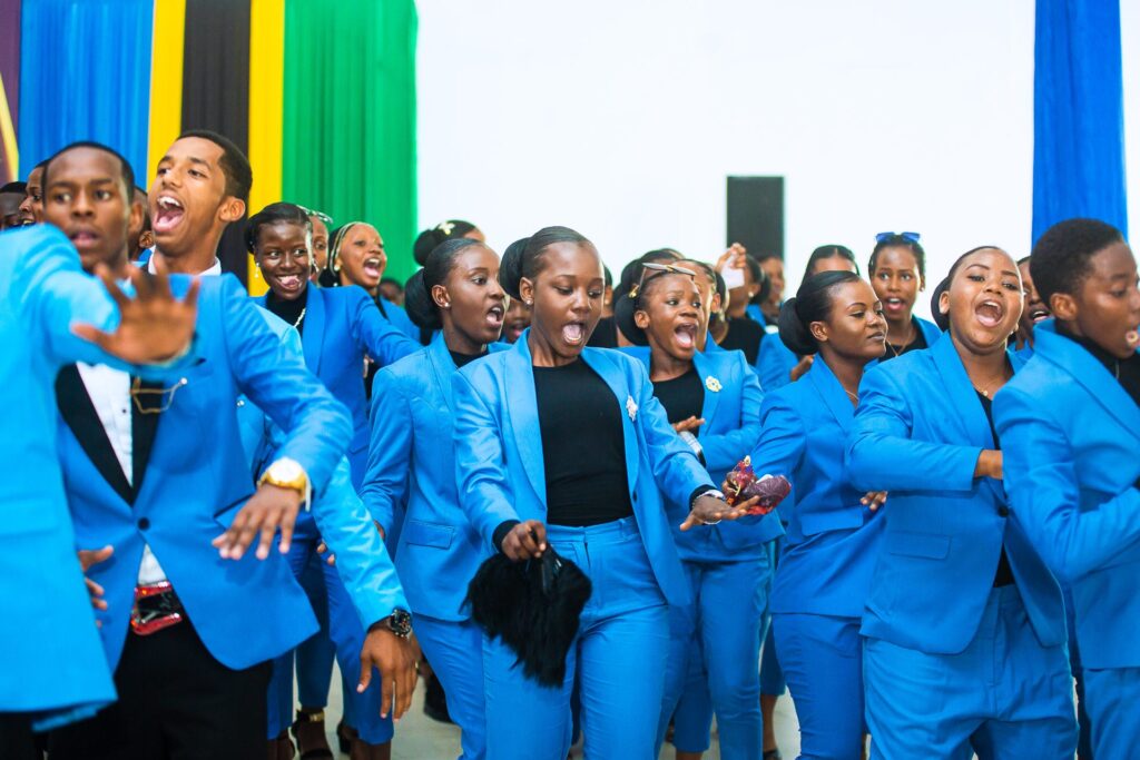 Song and celebration fill the hall as graduates arrive in their blue suits.