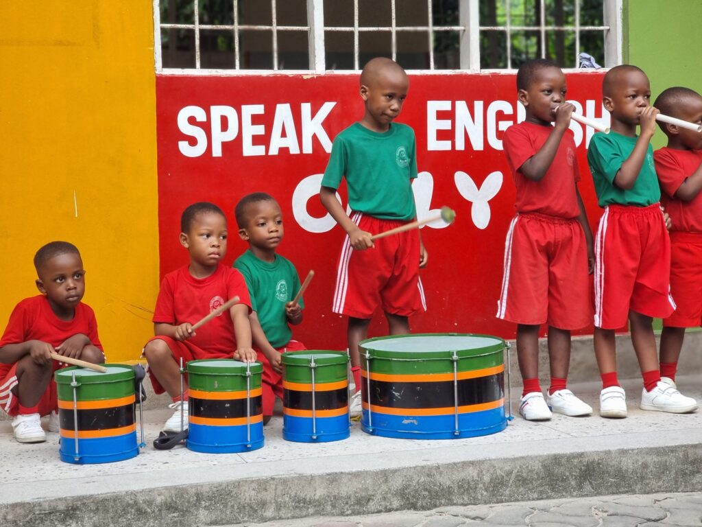 The little drum corps lines up by the Speak English wall.