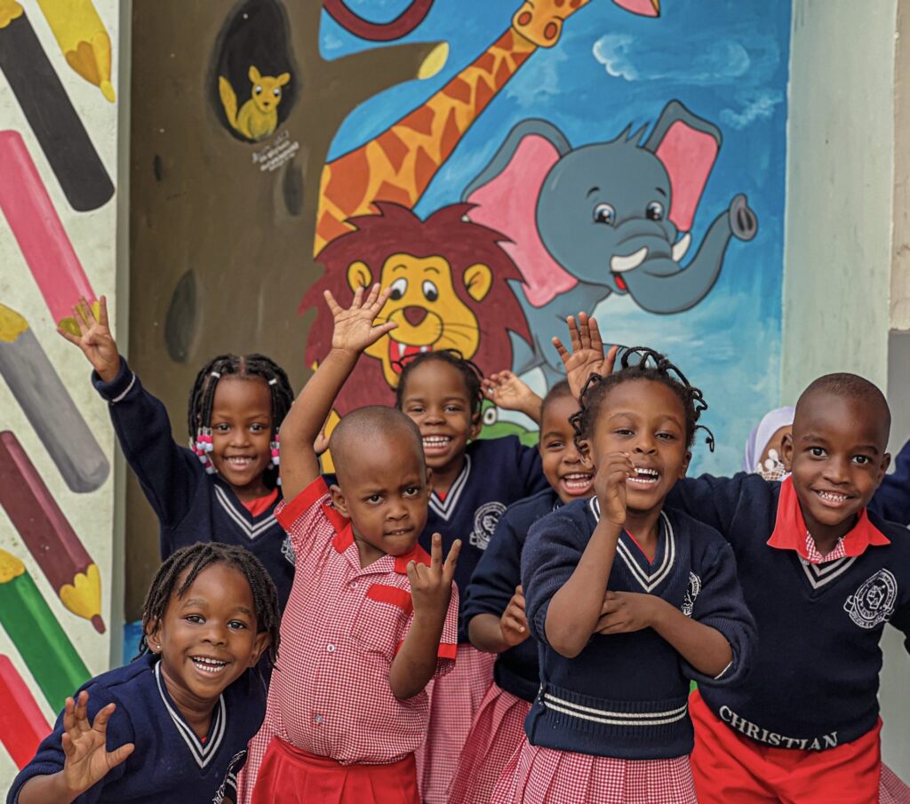 A cheer for the camera by the nursery mural.